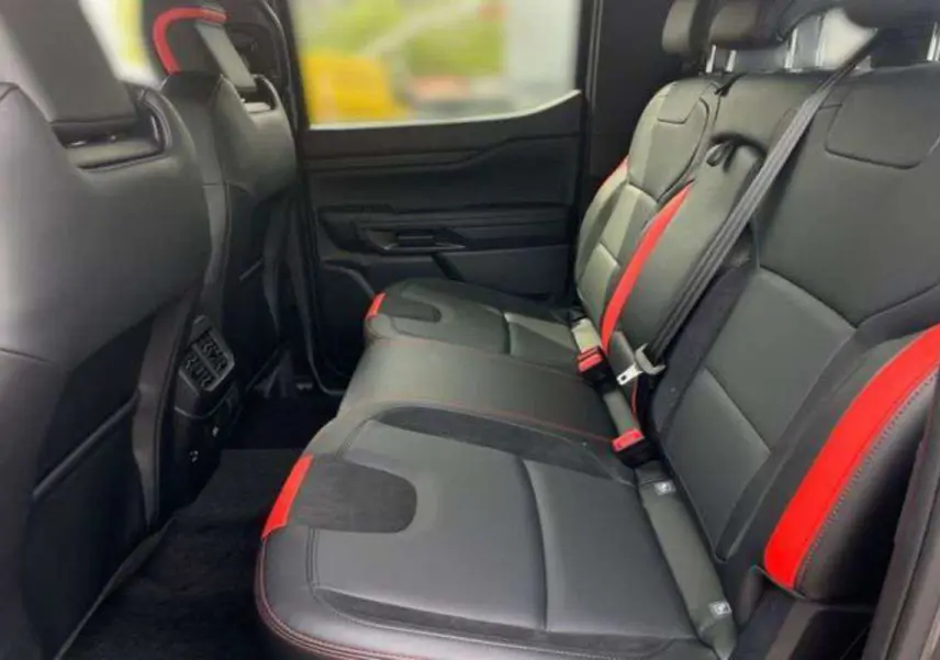 Vue intérieure arrière du Ford Ranger Raptor 2025 avec sièges noirs et inserts rouges contrastants.
