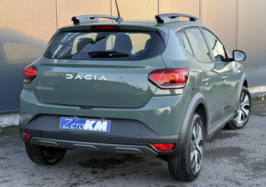 Vue 3/4 arrière droite d'une Dacia Sandero Stepway 2025 en kaki lichen avec barres de toit et feux arrière LED en Y.