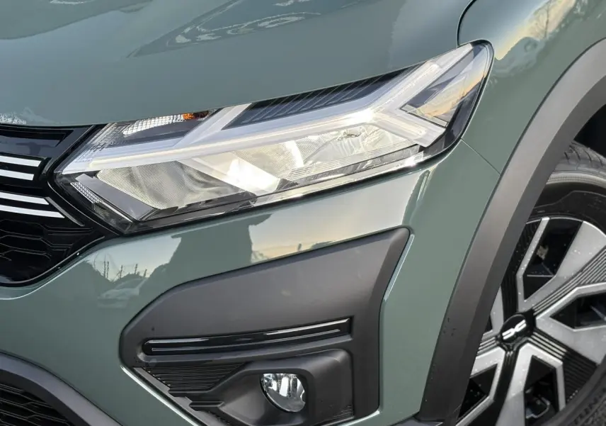 Gros plan sur l'avant droit du Dacia Sandero Stepway 2025 en kaki lichen, avec phares LED et enjoliveur de roue noir et argent.
