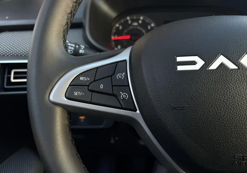 Gros plan sur le volant noir du Dacia Sandero Stepway 2025, avec commandes de régulateur de vitesse côté gauche.