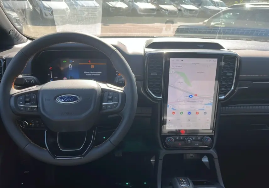 Vue intérieure du Ford Ranger 2025 2.3 PHEV Wildtrak Plus montrant le volant et l'écran tactile central lumineux.