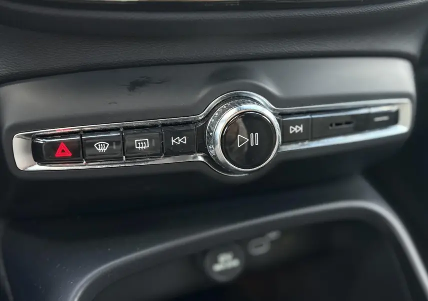 Gros plan sur la commande audio centrale noire et chrome du tableau de bord du Volvo XC40 2024.