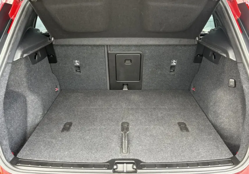 Coffre ouvert du Volvo XC40 rouge Fusion, montrant l'espace de chargement et la trappe centrale rabattable.