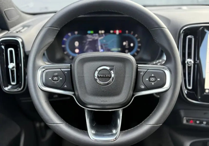 Volant cuir noir de Volvo XC40 2024 avec commandes intégrées et tableau de bord digital en arrière-plan.