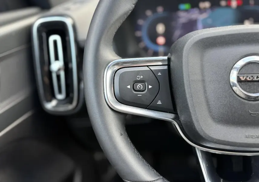 Gros plan sur la partie gauche du volant noir du Volvo XC40 2024 avec commandes de régulateur de vitesse.