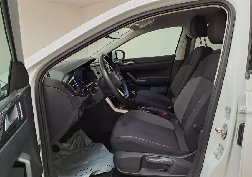 Vue intérieure côté conducteur du Volkswagen Taigo blanc pur 2024, montrant sièges tissu noirs et tableau de bord moderne.