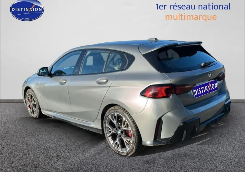 BMW Série 1 118da gris skyscraper vue 3/4 arrière droit avec jantes 18 pouces bicolores et becquet sportif.