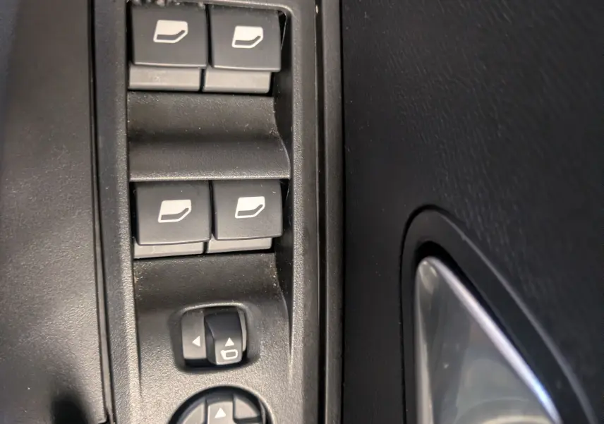 Gros plan sur les commandes des vitres électriques et rétroviseurs côté conducteur du Peugeot 2008 Hybrid 145 e-DCS6 GT 2025.