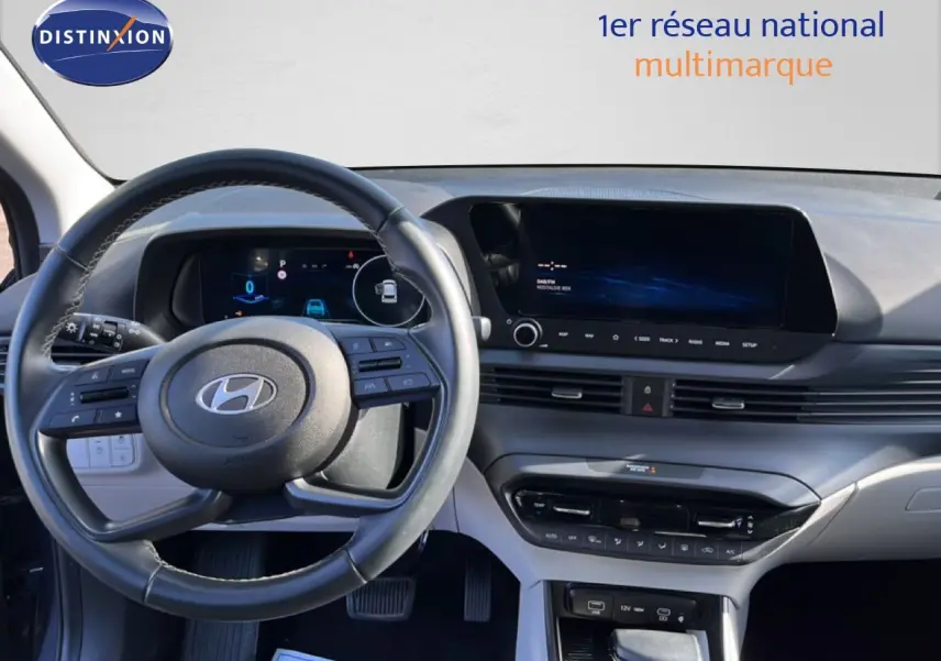 Vue intérieure du tableau de bord et volant de la Hyundai i20 2025 en gris Aurora Metal, avec écran tactile et commandes au volant.