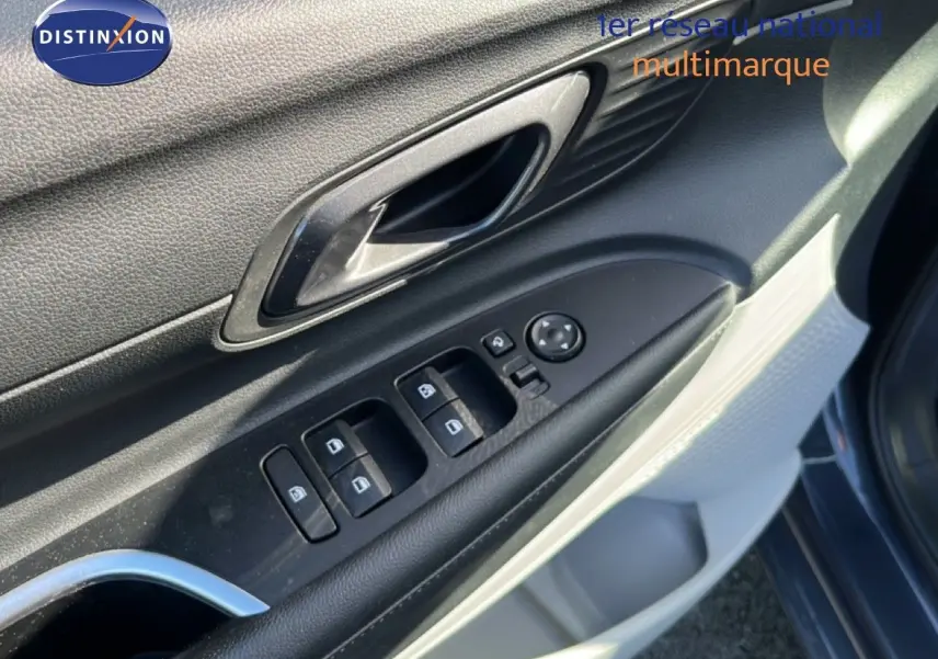Gros plan sur la porte côté gauche de la Hyundai i20 gris Aurora Metal, montrant les commandes des vitres et la poignée intérieure.