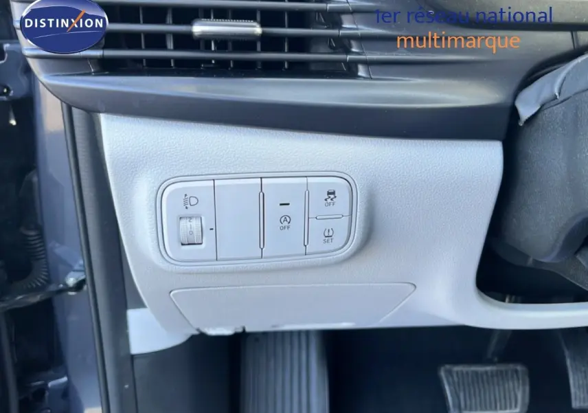 Gros plan sur les commandes de réglage des phares et aides à la conduite côté gauche d’un Hyundai i20 gris Aurora 2025.