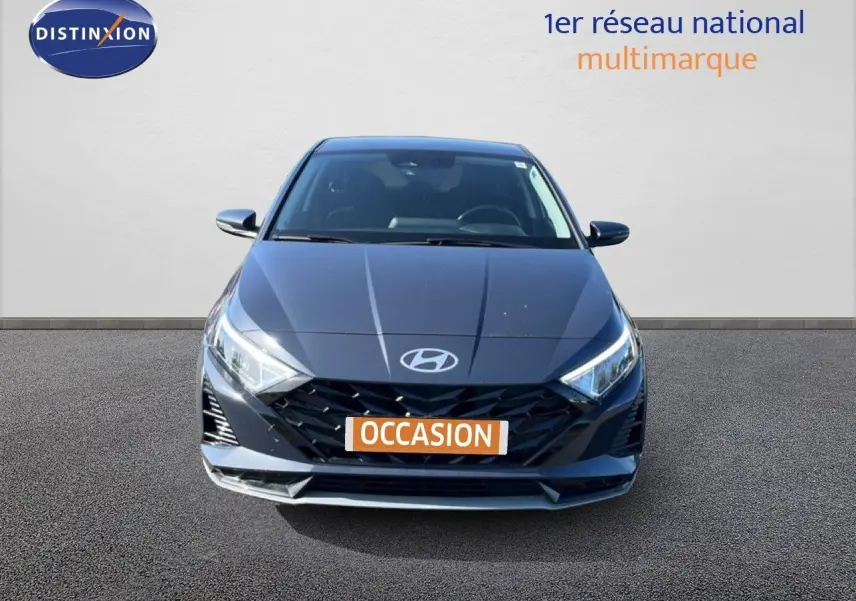 Vue avant d'une Hyundai i20 2025 gris aurora metal avec calandre noire et phares LED allumés.