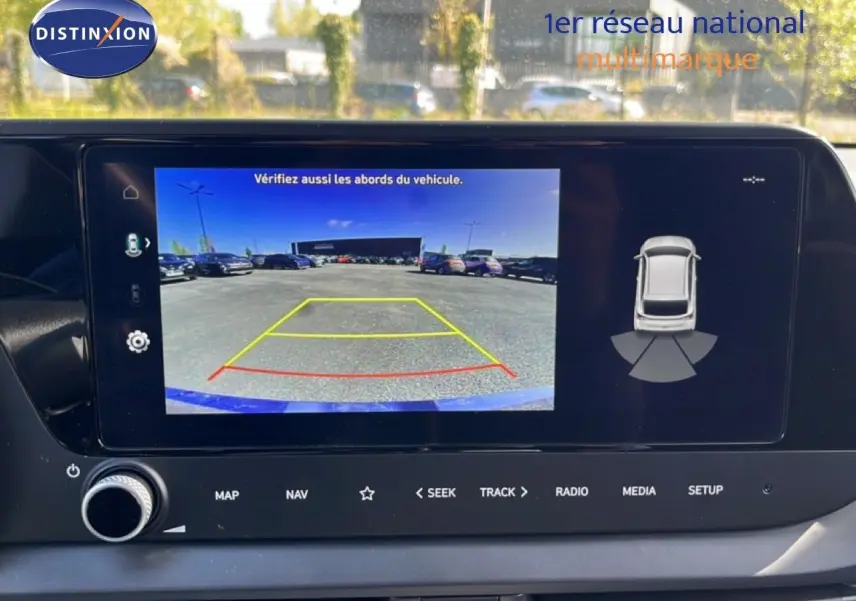 Écran central de la Hyundai i20 2025 montrant la caméra de recul avec lignes de guidage colorées en extérieur.