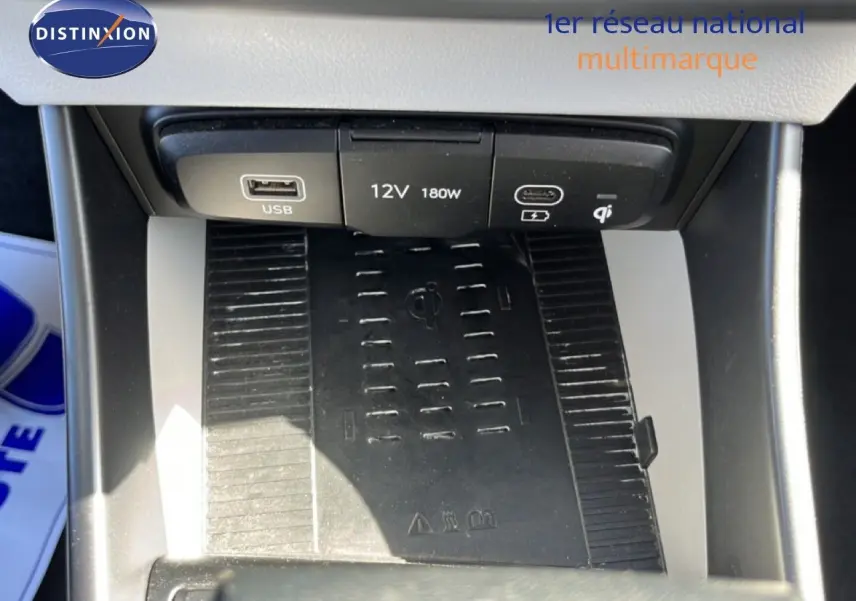 Vue rapprochée de la console centrale de la Hyundai i20 2025, montrant les ports USB, prise 12V et chargeur sans fil noir.