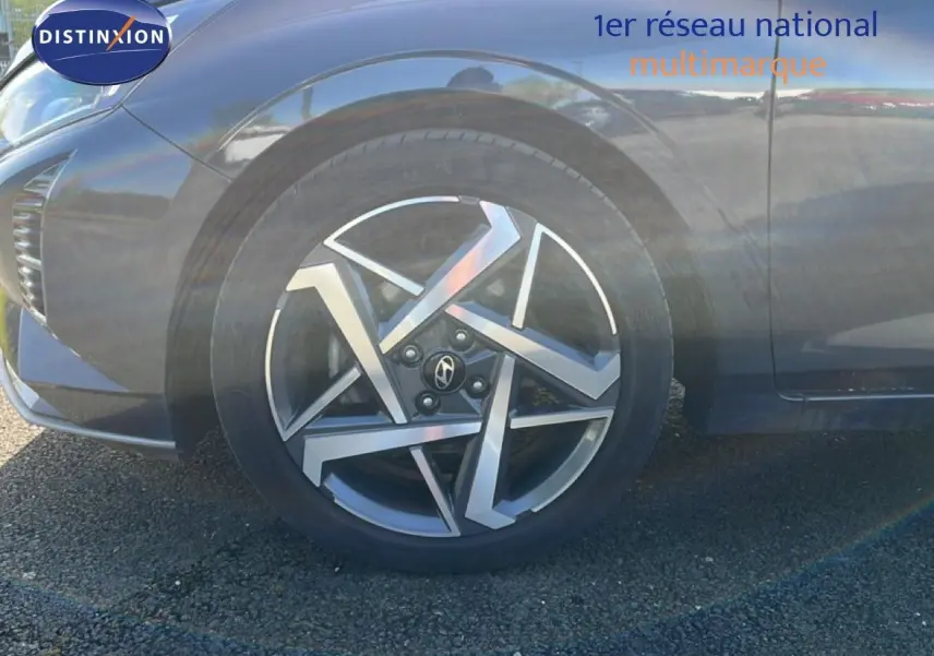 Gros plan sur la roue avant droite d'une Hyundai i20 gris aurora métal avec jante alliage au design géométrique.