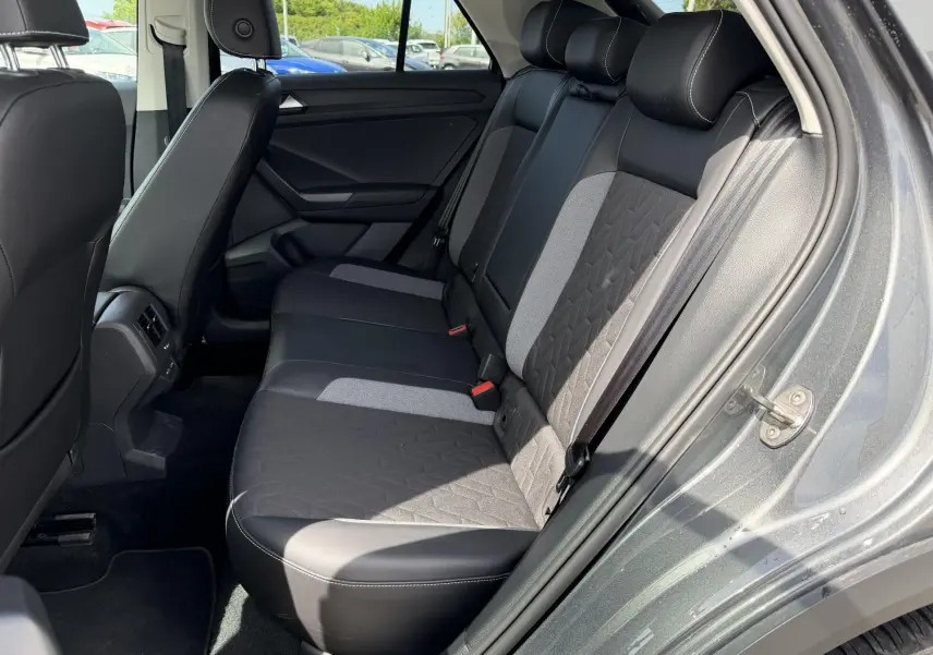 Vue côté droit de l'intérieur arrière du Volkswagen T-Roc gris 2025, avec sièges bicolores en tissu et cuir.