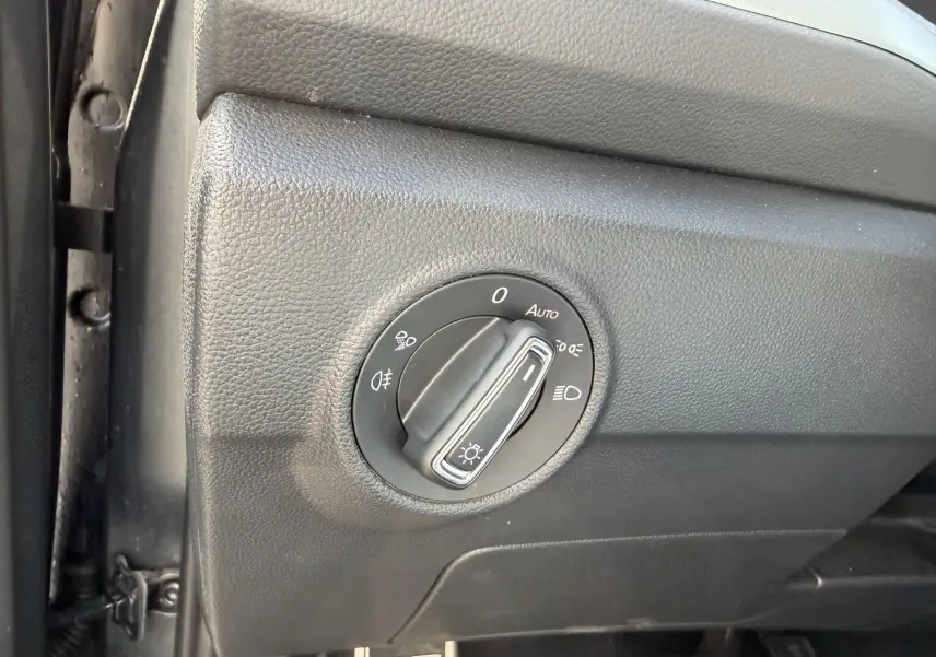 Gros plan sur le bouton de commande des phares dans l'habitacle noir du Volkswagen T-Roc 2025.