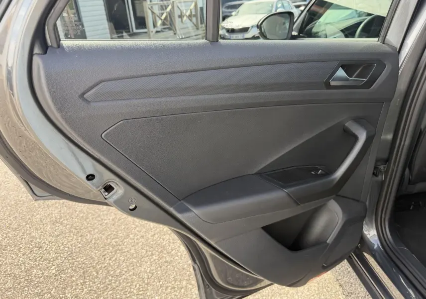 Vue intérieure de la porte arrière gauche grise du Volkswagen T-Roc 2025 avec poignée et commande de vitre intégrée.