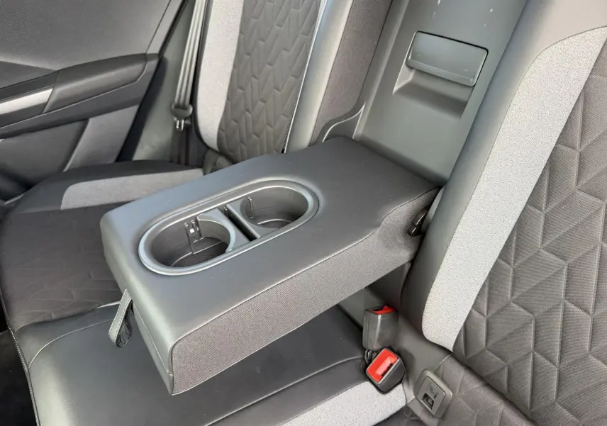 Vue rapprochée de l'accoudoir central arrière avec porte-gobelets sur les sièges bicolores gris du Volkswagen T-Roc 2025.