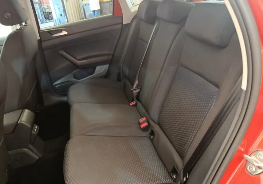 Vue intérieure côté droit des sièges arrière noirs d'une Volkswagen Polo orange, avec ceinture de sécurité visible.