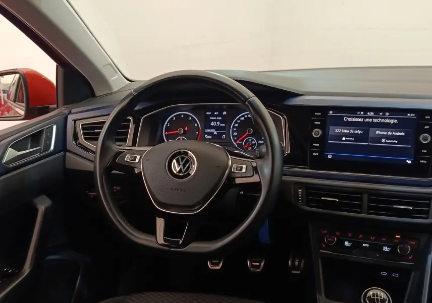 Vue intérieure centrée sur le volant cuir alu et tableau de bord numérique de la Volkswagen Polo orange 2020.