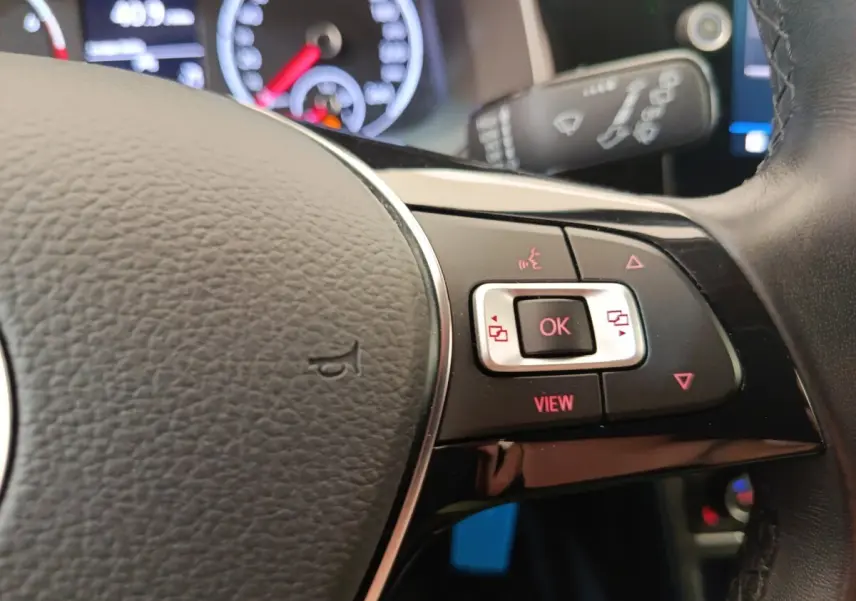 Gros plan sur le volant cuir et alu de la Volkswagen Polo 1.0 TSI 95 United avec commandes multifonctions rouges.