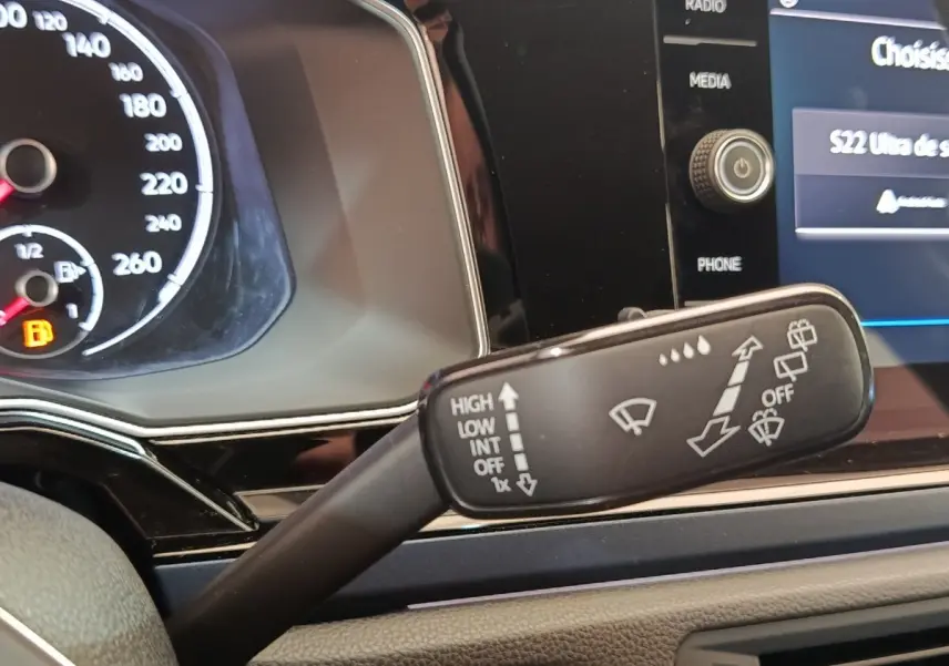 Gros plan intérieur sur le commodo d’essuie-glaces de la Volkswagen Polo 1.0 TSI 95 United, tableau de bord noir visible.