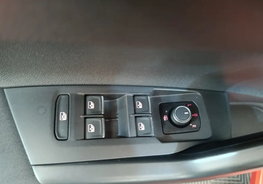 Commande des vitres électriques et réglage des rétroviseurs sur la porte côté conducteur d’une Volkswagen Polo orange.