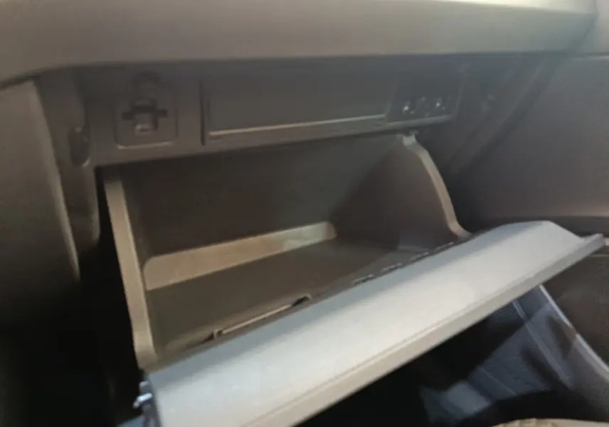 Gros plan sur la boîte à gants ouverte côté passager dans l'habitacle noir d'une Volkswagen Polo orange 2020.