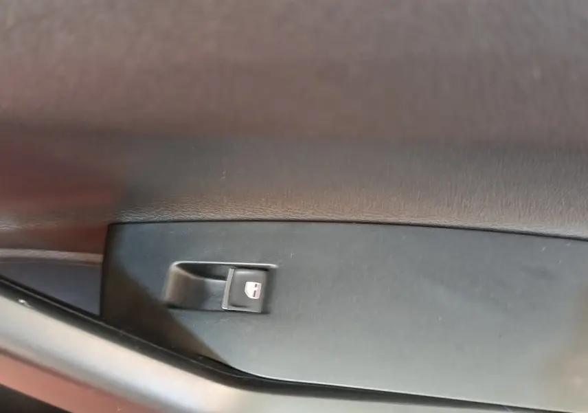 Détail du bouton de verrouillage des portes sur la porte intérieure côté conducteur d'une Volkswagen Polo orange.