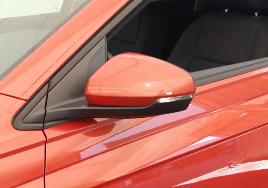 Gros plan sur le rétroviseur côté gauche d'une Volkswagen Polo orange 2020 avec portière et siège noir visibles.