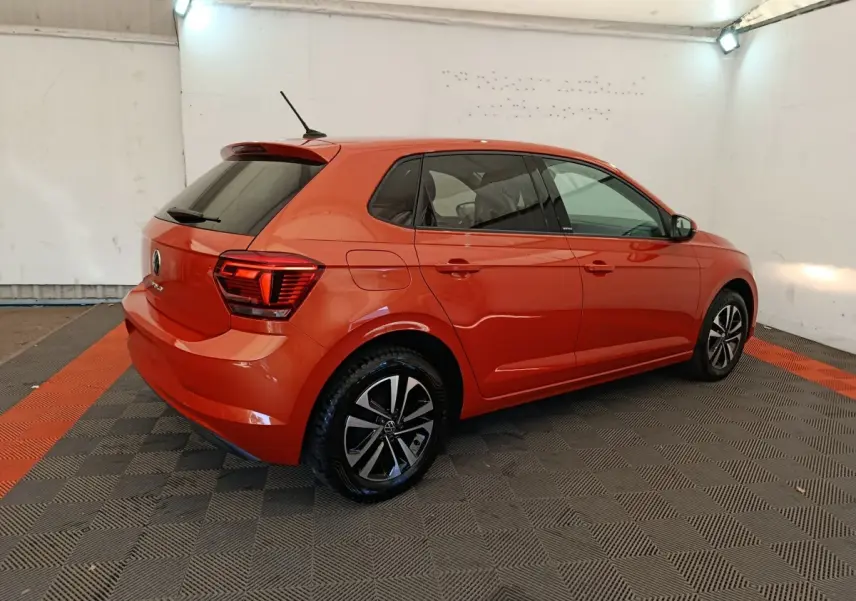 Volkswagen Polo 1.0 TSI 95 United orange vue 3/4 arrière droit dans un garage avec jantes noires et argentées.
