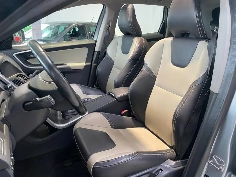 Vue intérieure côté conducteur du Volvo XC60 D4 argenté, sièges bi-ton cuir noir et beige avec volant multifonction.