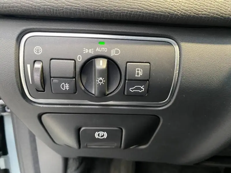 Panneau de commandes d'éclairage et ouverture du coffre sur tableau de bord noir d'un Volvo XC60 argenté de 2015.