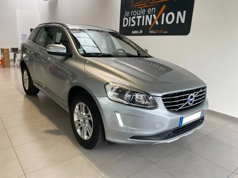 Volvo XC60 argenté vu de 3/4 avant droit en intérieur, avec calandre chromée et jantes alliage visibles.