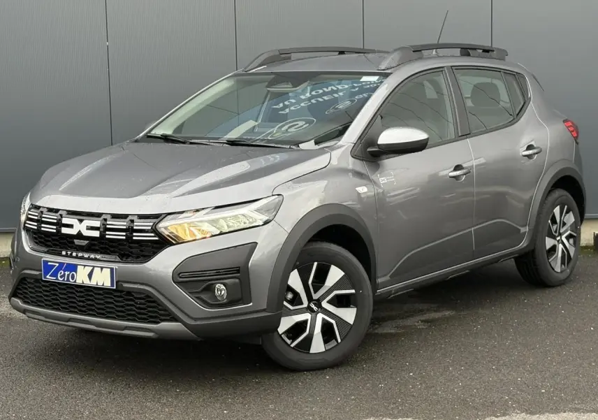 Vue 3/4 avant d'une Dacia Sandero Stepway 2025 gris schiste avec barres de toit et jantes spécifiques Atara Dark.