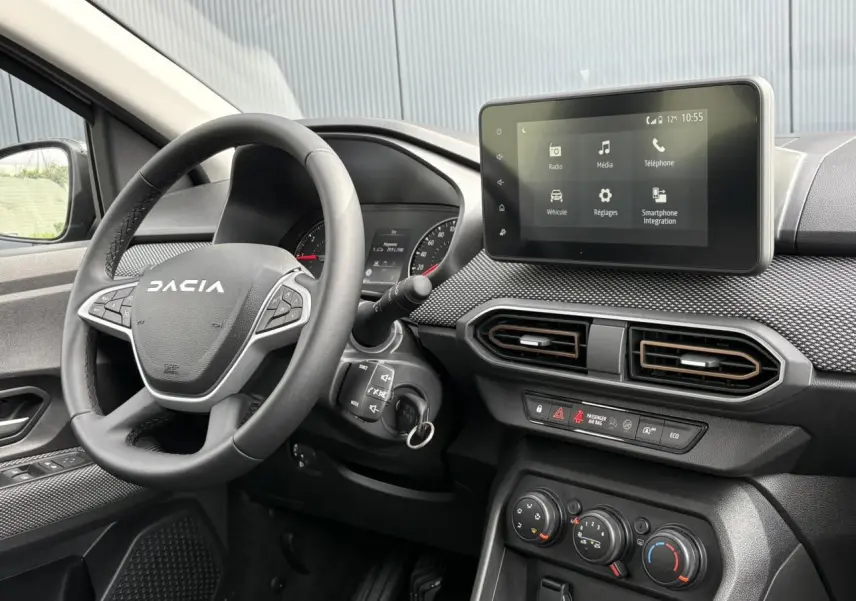 Vue intérieure côté conducteur du tableau de bord gris foncé de la Dacia Sandero Stepway 2025 avec écran tactile et volant marqué Dacia.