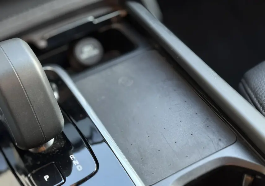 Gros plan sur la console centrale noire du Volvo XC90 T8 hybride 2024 avec levier de vitesses automatique et chargeur induction.