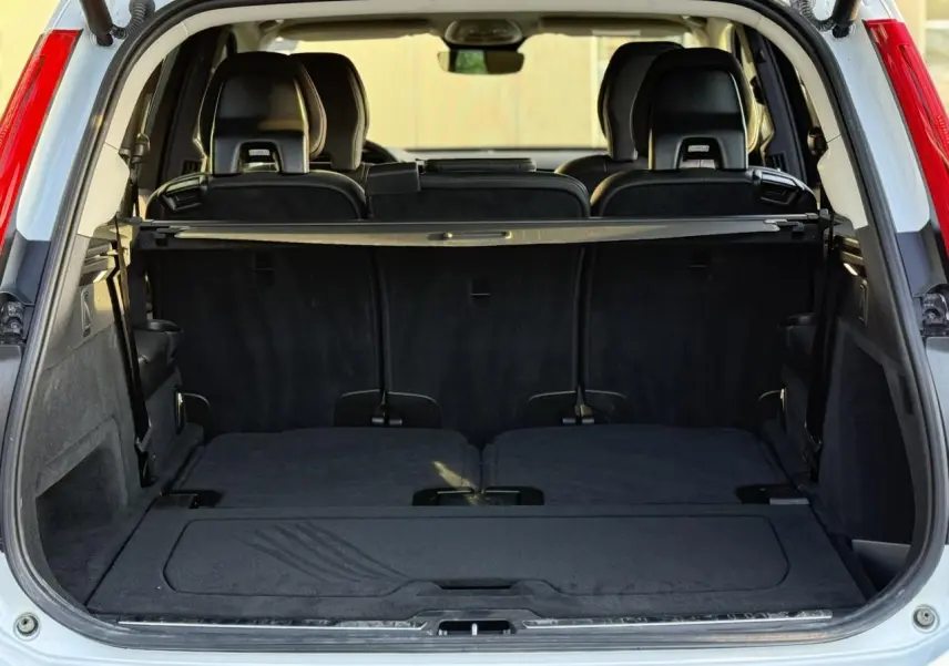 Coffre ouvert vu de l'arrière d'un Volvo XC90 blanc Crystal, montrant les sièges rabattus et l'intérieur noir.