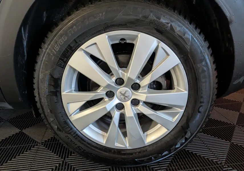 Gros plan sur la jante argentée d’une Peugeot 3008 gris Arthense, mettant en valeur le logo lion central.