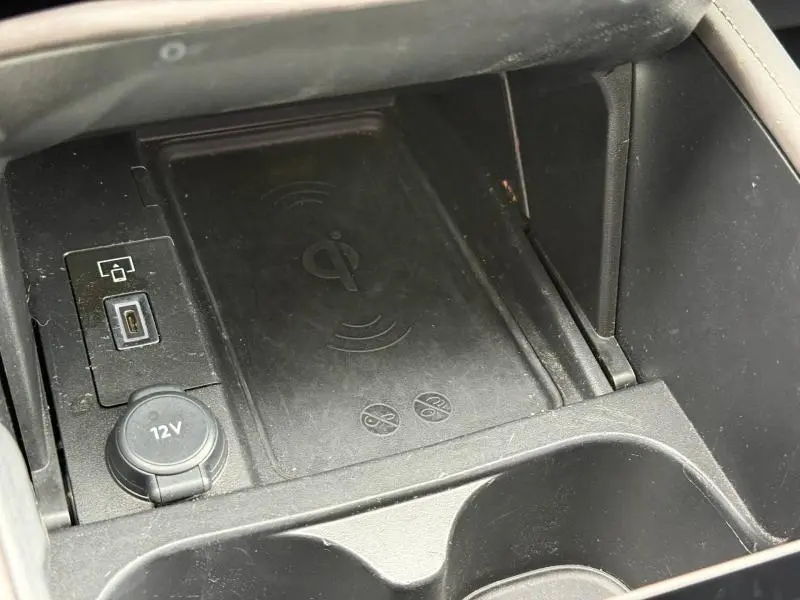 Gros plan sur la console centrale noire du DS4 2023, montrant un chargeur sans fil Qi et une prise 12V.