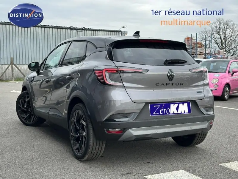 Vue 3/4 arrière droite du Renault Captur 2026 gris Cassiopée/Noir Étoilé avec jantes noires et logo Alpine visible.