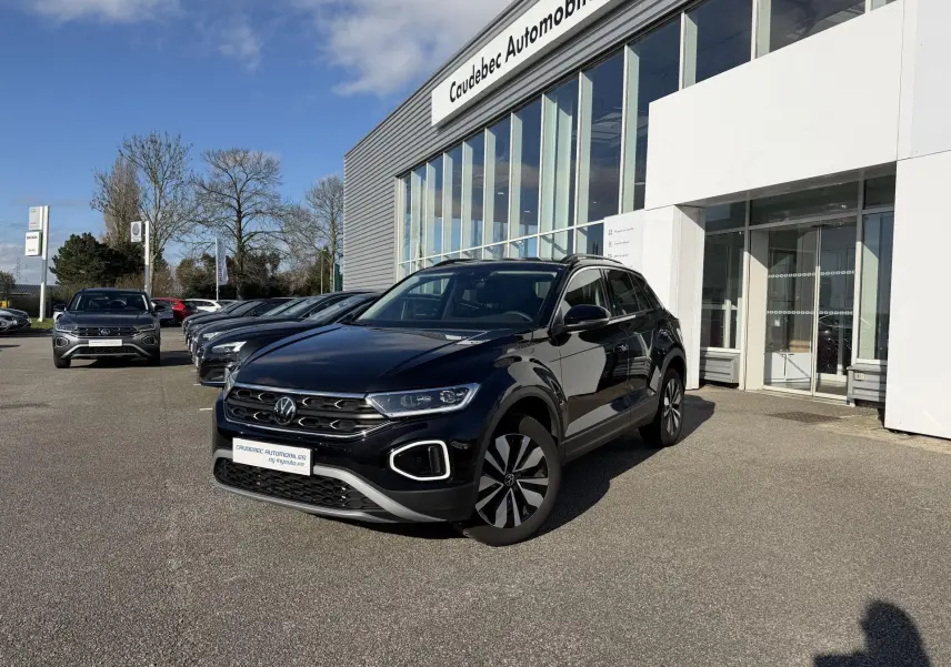 Volkswagen T-Roc noir en 3/4 avant droit, stationné devant un showroom avec jantes alliage et calandre distinctive.