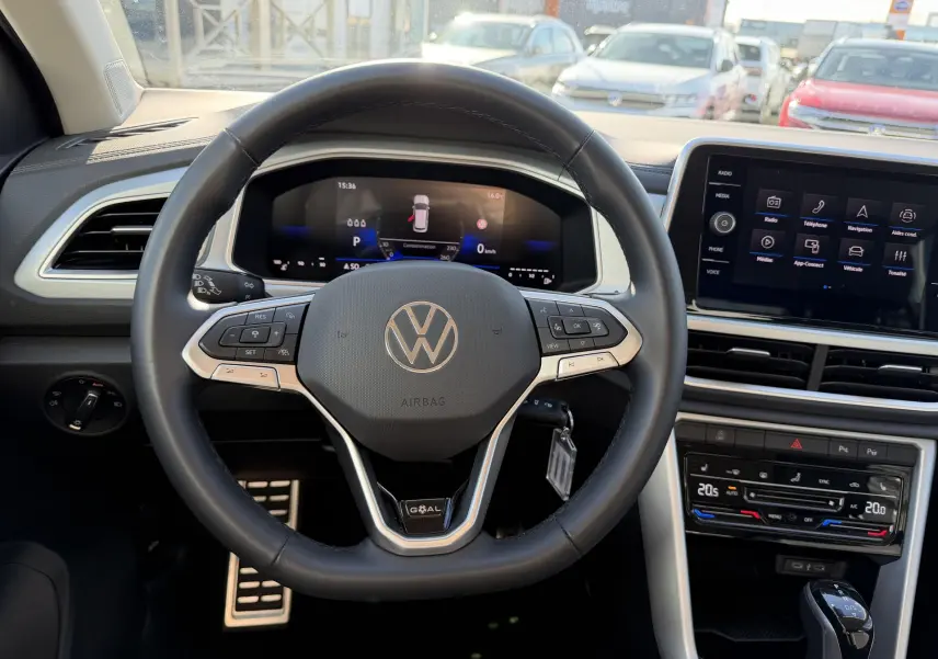 Vue intérieure centrée sur le volant cuir multifonctions noir du Volkswagen T-Roc 2025 avec écran digital et console tactile.