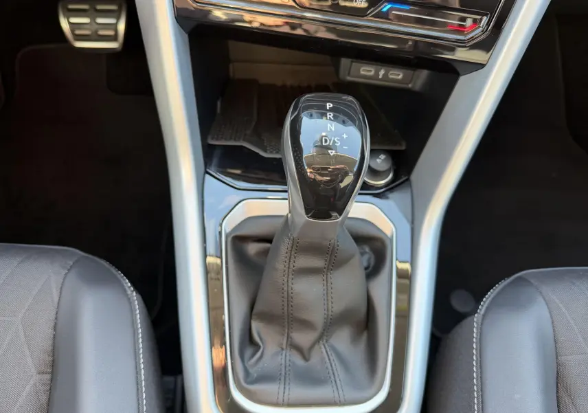 Vue rapprochée du levier de vitesses DSG7 noir et gris du Volkswagen T-Roc 2025, entouré des sièges avant en cuir noir.