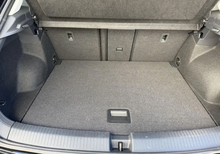 Coffre spacieux et propre du Volkswagen T-Roc noir, vue intérieure arrière avec revêtement gris et poignée centrale.