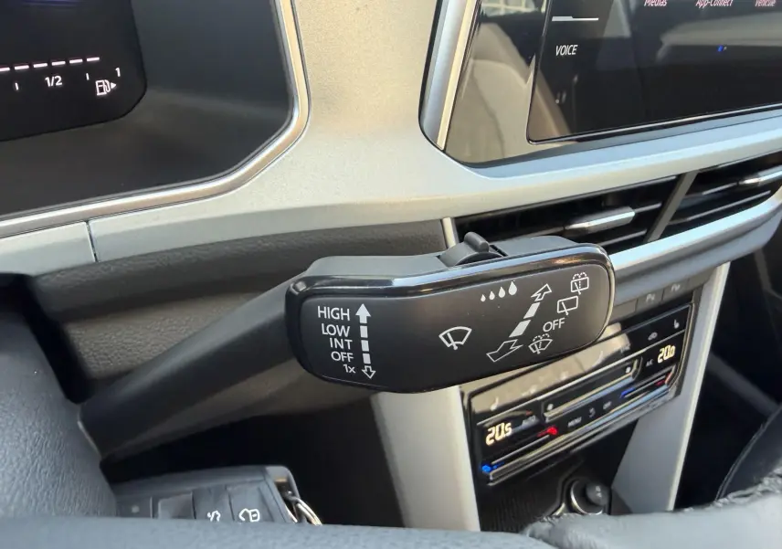 Gros plan sur la commande d'essuie-glace à gauche du volant dans l'habitacle du Volkswagen T-Roc noir 2025.