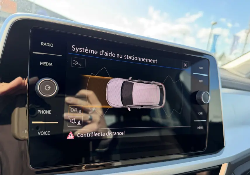 Écran tactile intérieur affichant le système d'aide au stationnement du Volkswagen T-Roc, vue rapprochée du tableau de bord.