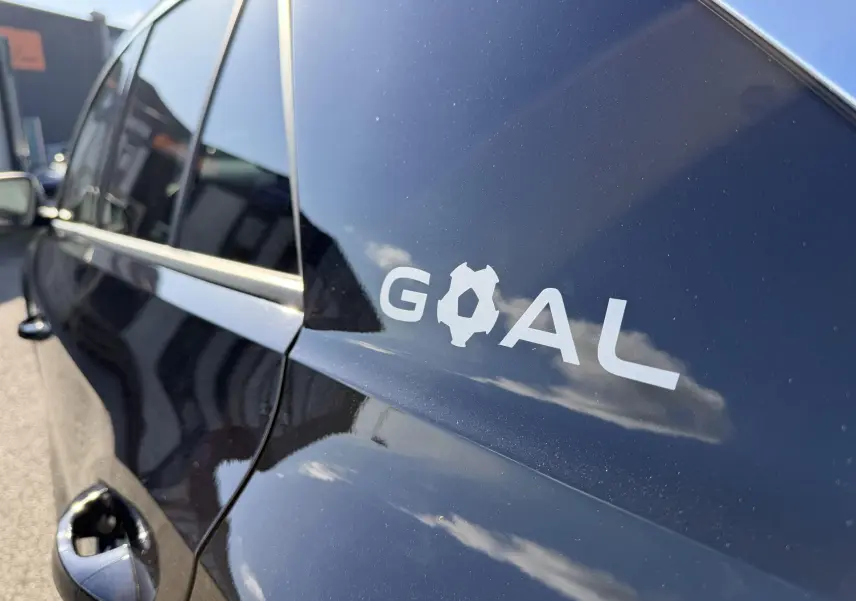 Vue rapprochée côté gauche arrière du Volkswagen T-Roc noir avec logo "GOAL" sur la carrosserie.