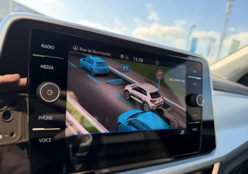 Écran tactile central montrant l’aide au stationnement avec vue 3D des véhicules et signalisation routière.